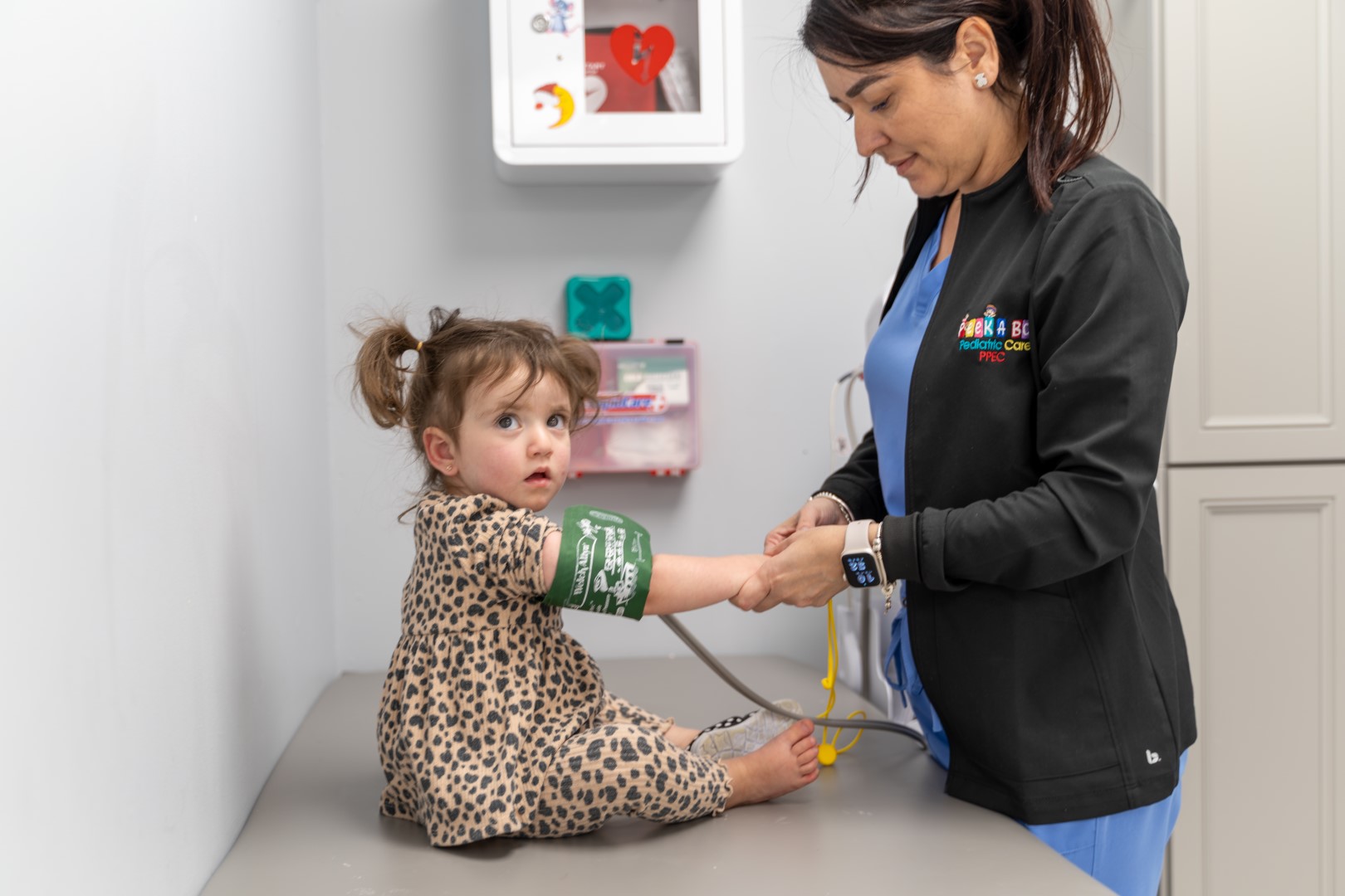 A nurse checking a young child's blood pressure in the treatment room at Peek A Boo PPEC